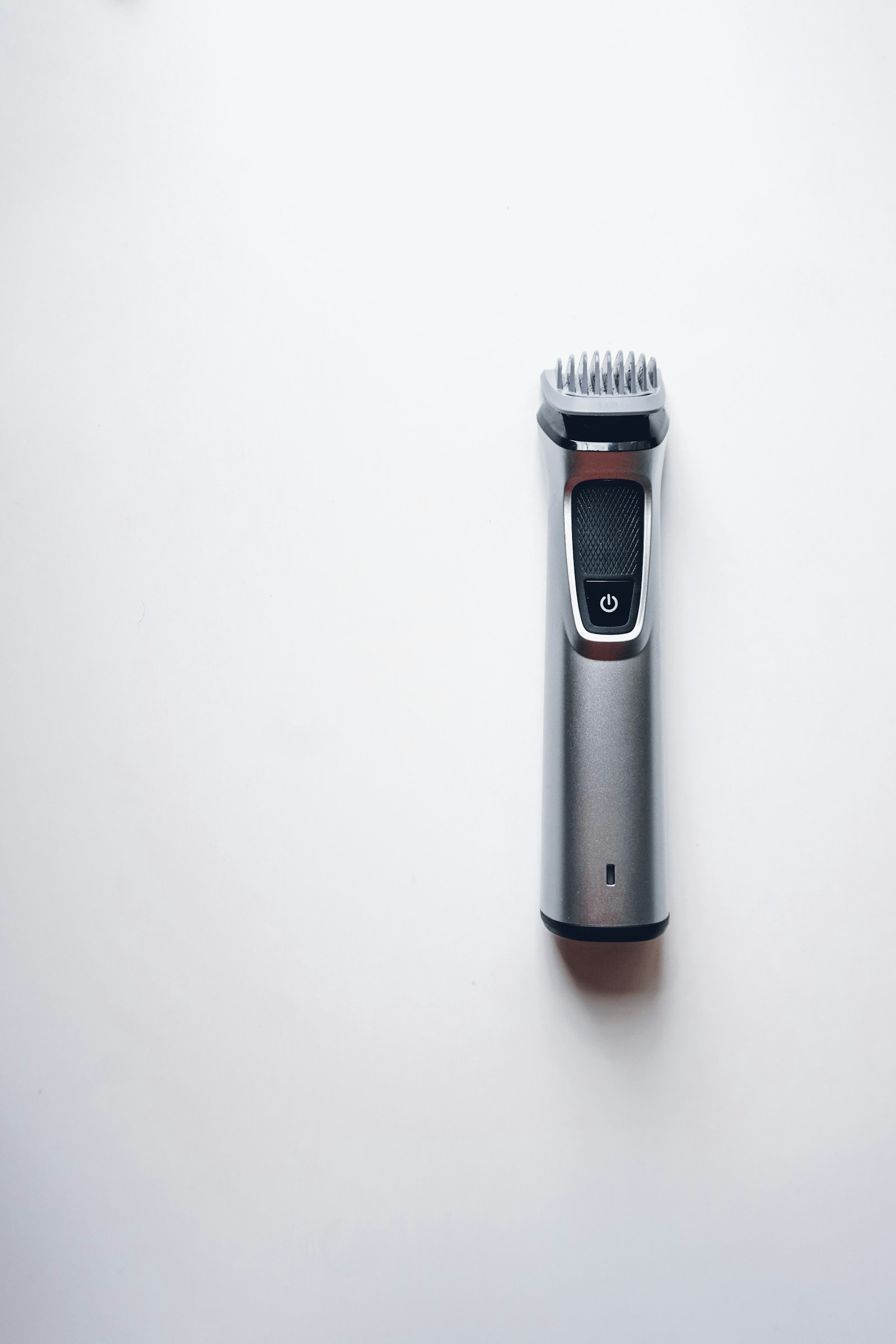 Professional hair clipper and styling comb on a light surface