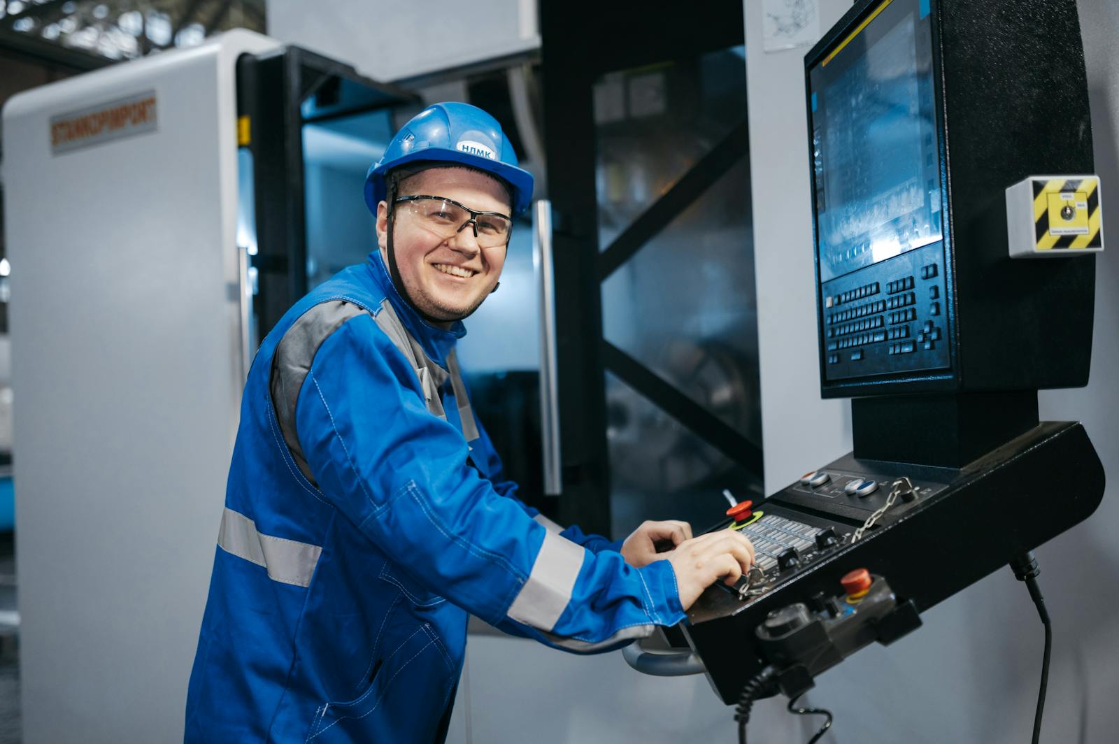 Engineer in a blue hard hat and uniform operating industrial equipment