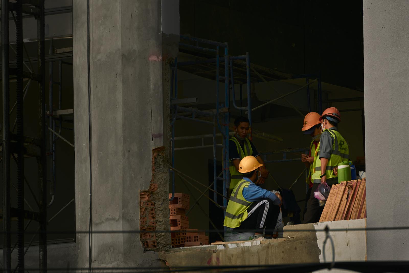 Construction workers in orange and yellow hard hats with high-visibility safety vests